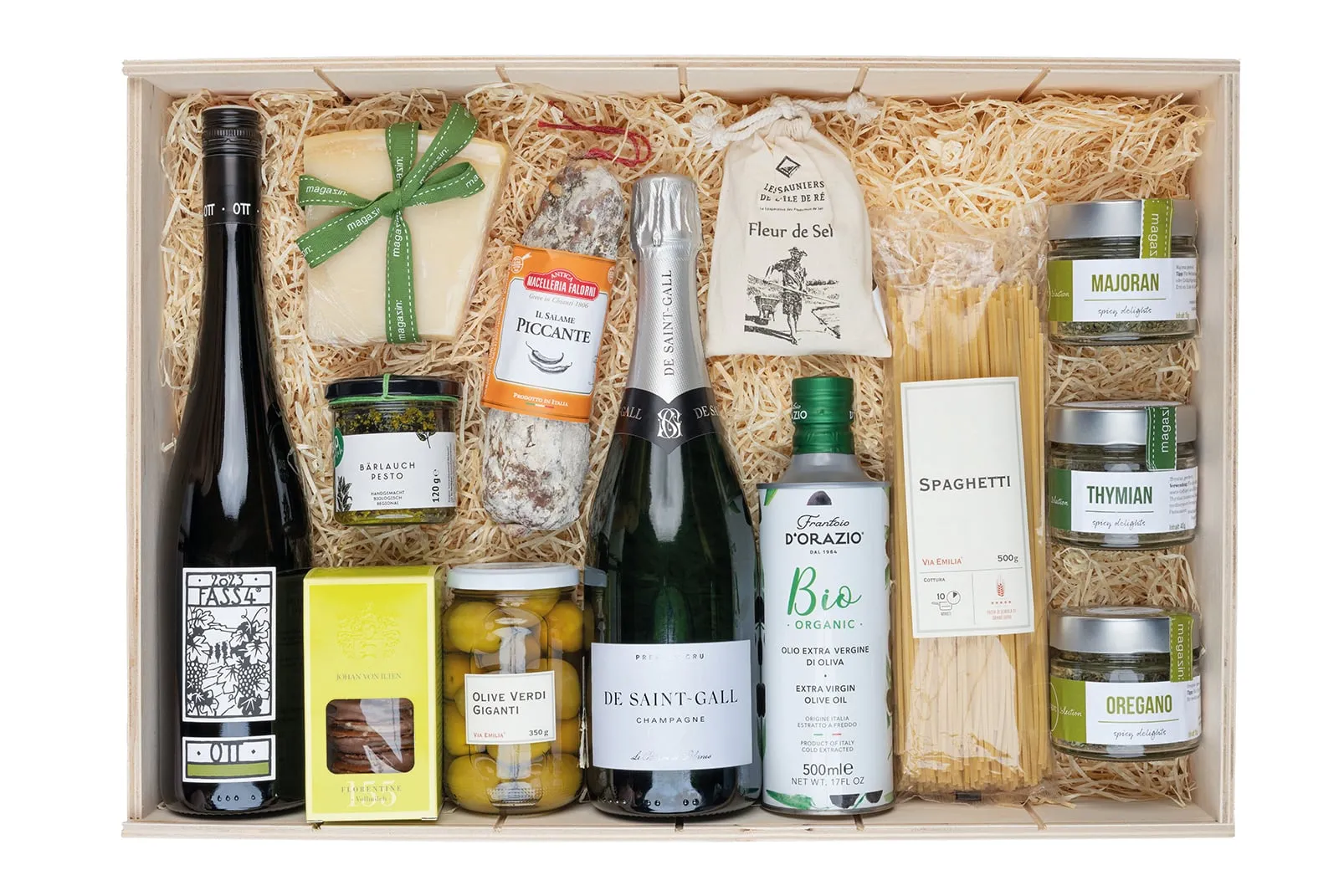 Geöffnete Holz-Geschenkkiste mit Grünem Veltliner, Champagner, Parmigiano, Salami, Pesto, Oliven, Olivenöl, Spaghetti und Gewürzen auf Holzwolle